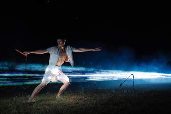 A dancer moving in front of a beam of blue light