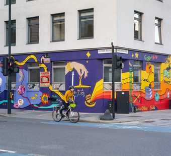 A person cycles past a mural painted on a building