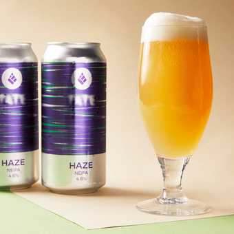 beer in a glass with two tins behind it that say 'tate and haze beer' on it