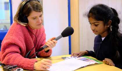 a person sits down with a child and records the child speaking