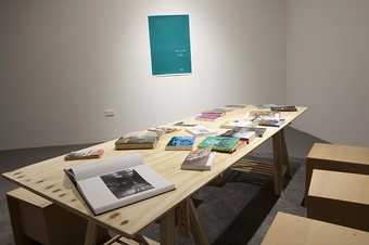 Installation view of The Long Note showing a large table with books on top 