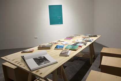 Installation view of The Long Note showing a large table with books on top