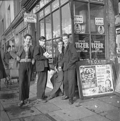 black and white photograph of four men outside a shop in East London around 1951