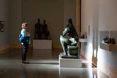a woman stands in front of a Henry Moore sculpture