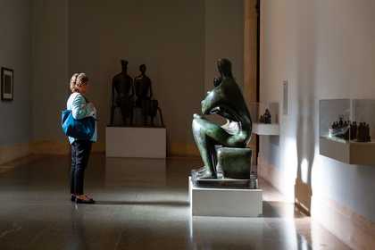 a woman stands in front of a Henry Moore sculpture