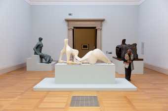 a woman stands and looks at a Henry Moore statue