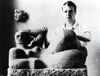 Photograph showing Henry Moore with his sculpture Reclining Figure and Mask