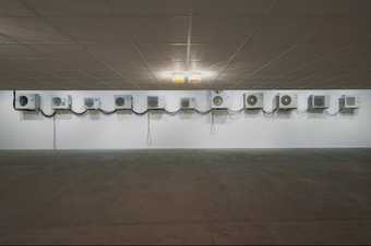 a series of air conditioning units are arranged in a line in a gallery space