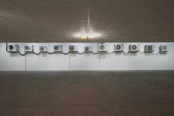 eleven industrial air conditioners are placed along the walls of the gallery