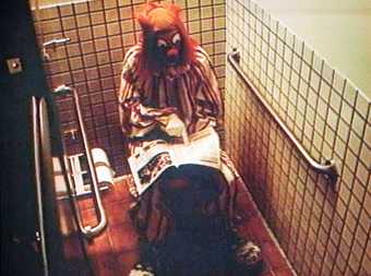 A clown sat in a toilet reading a newspaper