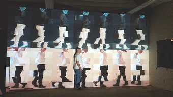 Image of a man walking past a projection of himself repeated multiple times