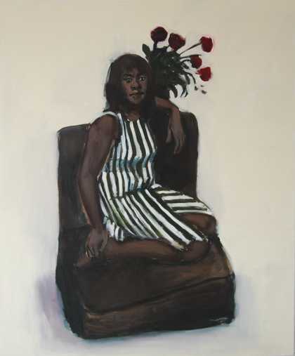 a woman wears a stripey dress and sits on a chair with a vase of roses in the background