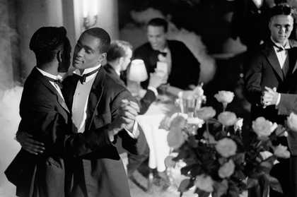 A black and white photograph of a male couple dancing and wearing tuxedos