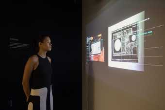 Installation shot of Recognition AI display at Tate Britain, showing a woman looking a projected screen