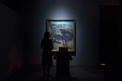 A woman stands with headphones on in front of Francis Bacon’s Figure in a Landscape 1945