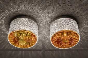 An image of two lead crystal lamps with a mixture of palm oil and cognac applied to the inside. They cast patterns of light onto a ceiling