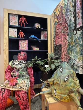 A display of monster-looking sculptures shown on chairs and displayed on shelves in the background.