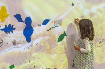 A girl draws on a big piece of fabric hanging in front of her