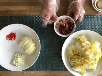 a pair of hands seen from above, preparing Kimchi