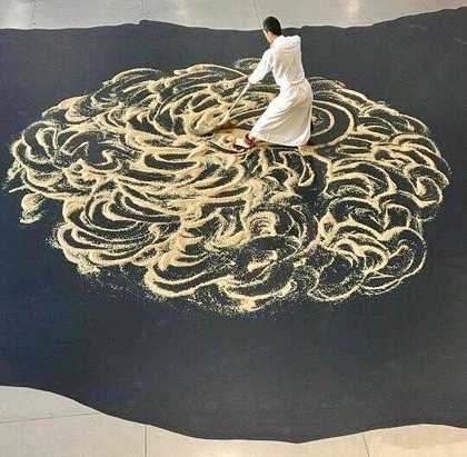 A man sweeps sand in Lee Mingwei's performance work