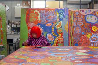 The artist Yayoi Kusama works on one of her large-scale paintings in her studio in Tokyo