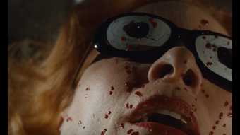 Close up image of a woman with googles on with blood splattered on her face