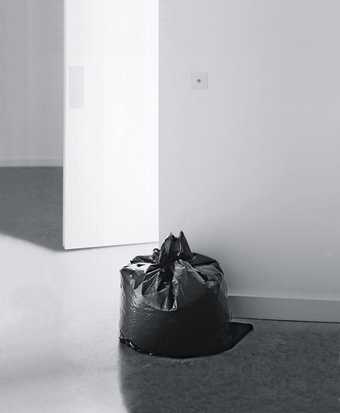 Installation view of Ceal Floyers Garbage Bag at Ikon Gallery Birmingham 2001 photograph of a black bin bag against a white gallery wall