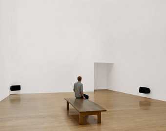 Installation view of Turner Prize winner Susan Philipszs Lowlands at Tate Britain October 2010 photograph of a white gallery with two audio speakers and a visitor sat on a bench 