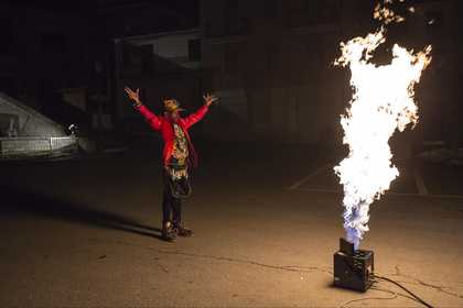 A man with raised hands looks at large flames