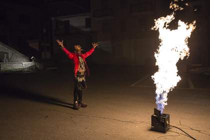 A man with raised hands looks at large flames
