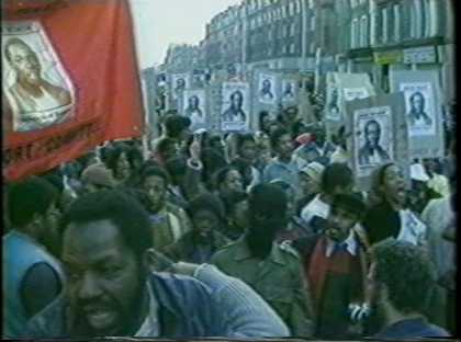 Close up of people holding placards with a portrait of a black man on it at a protest 