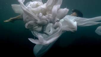 A person underwater wearing billowing white fabric