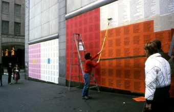 Man pasting Holzer's work onto a wall