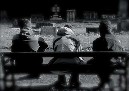 Black and white photograph of three boys in hoodies sitting on a bench