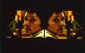 Isaac Julien Vagabondia 2000, video still showing two mirrored image frames of a headshot of a woman and a man in the background