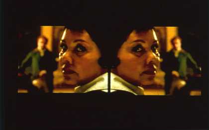 Isaac Julien Vagabondia 2000, video still showing two mirrored image frames of a headshot of a woman and a man in the background