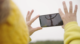 a person holds a phone which has a digital figure on their screen