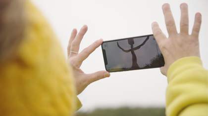 a person holds a phone which has a digital figure on their screen