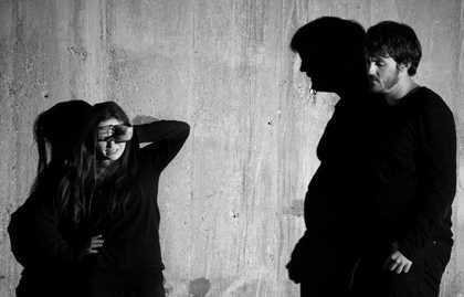  A black and white image of a man and a woman leaning against a wall