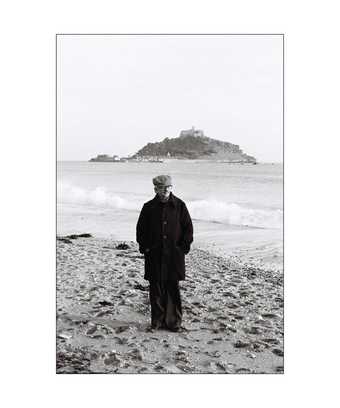Photo of Khakhar standing on a beach in Cornwall. Fully dressed wearing a cap