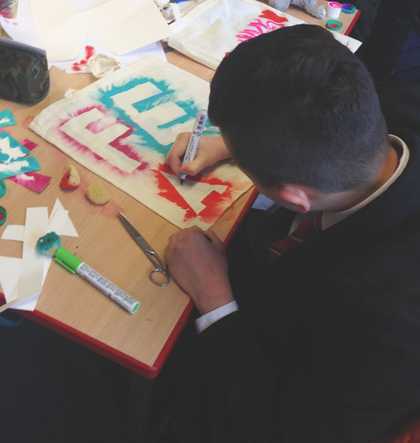Kid using a stencil to paint on a bag