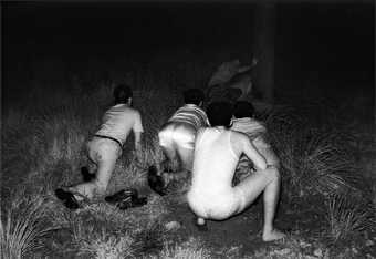 Kohei Yoshiyuki untitled 1971-1979 from the series the park a photograph of men crouched down surrounded by grass
