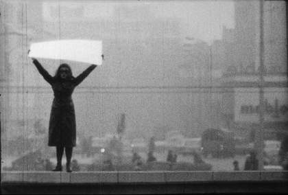 KwieKulik Open Form – Tribune of Honour, Poland 1971, black and white photo of woman holding up big white paper over her head