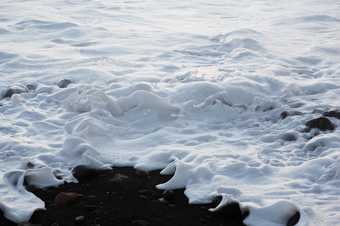 Colour photograph of white waves on a coast