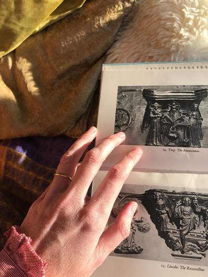 Olivia Laing holds open a copy of Misericords: Medieval Life in English Woodcarving (1954)