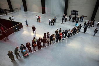 Aerial photograph of a group of people positioned along a white line drawn across the Turbine Hall floor at Tate Modern