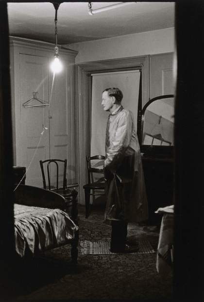 Man standing in a room, his legs are facing backwards but his torso is forwards