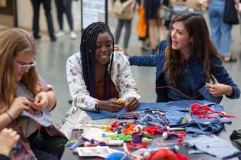three women sit and sew and make at a table in Tate Britain