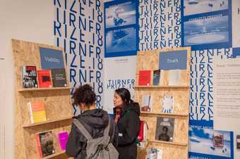 two women browse the 'power' and 'truth' bookshelves in the gallery
