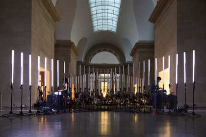 Two people playing instruments to the backdrop of vertical white light tubes